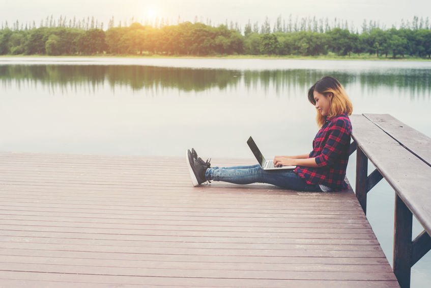 girl sitting on small bridge with laptop